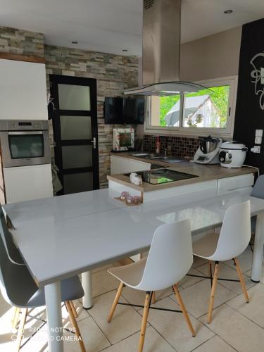 - une cuisine avec une table et des chaises blanches dans l'établissement Familly 10 min du circuit 15 min de boulerie jump et 1h30 de Paris Saint Arnoult en voiture ou 55 min en train pensez aux JO, à Changé