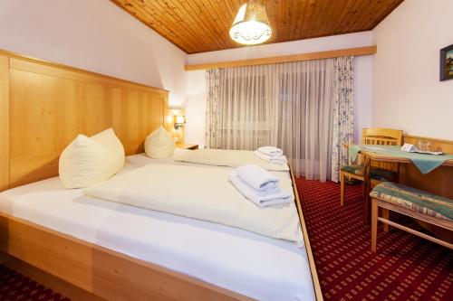 a bedroom with a large white bed with a desk at Ruperti - Gästehaus in Ainring