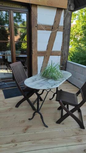 a patio table and two chairs on a deck at GITE AU PETIT RUISSEAU-Etage et combles-maison alsacienne 4 personnes 4 nuitées minimum in Langensoultzbach