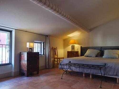 a bedroom with a bed and a chair and a window at La petite hostellerie in Uzès