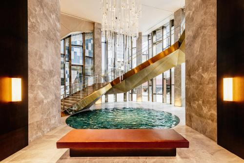 einen Pool in einer Lobby mit einer Treppe in der Unterkunft The Ritz-Carlton, Melbourne in Melbourne