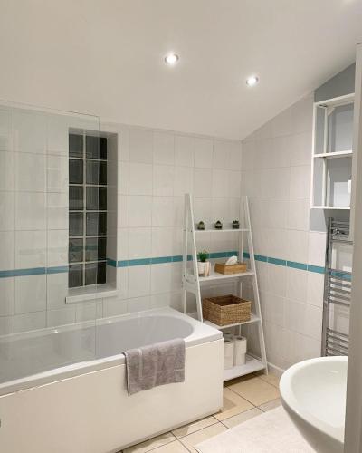 a white bathroom with a tub and a sink at Cardiff Home in Cardiff