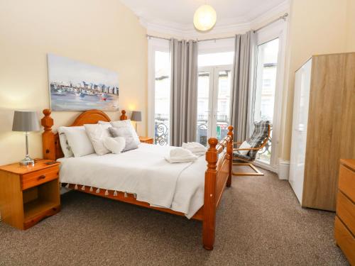 a bedroom with a bed with white sheets and windows at Clover Court in Great Yarmouth