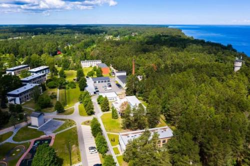 an aerial view of a campus with trees and the ocean at Three By The Sea apartments at Albatross Home in Ķesterciems