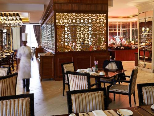 a chef walking through a restaurant with tables and chairs at Villa Rosa Kempinski in Nairobi