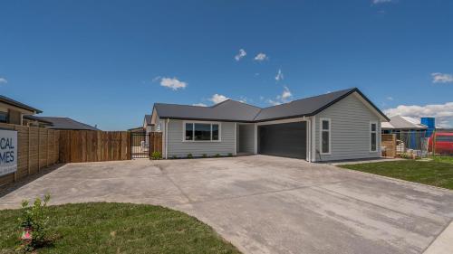 a house with a garage in a yard at Hosts on the Coast Kick Back on Kupe in Whitianga