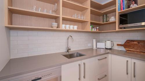 a kitchen with white cabinets and a sink at Hosts on the Coast Kick Back on Kupe in Whitianga