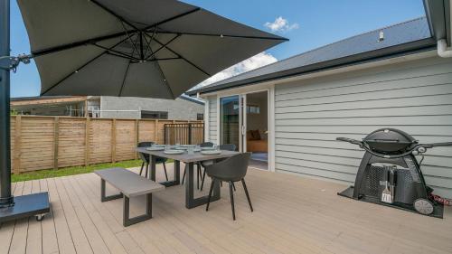 a patio with a table and chairs and an umbrella at Hosts on the Coast Kick Back on Kupe in Whitianga