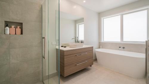a bathroom with a sink and a bath tub and a window at Hosts on the Coast Kick Back on Kupe in Whitianga