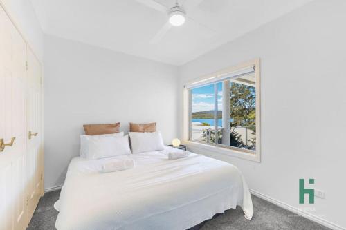 a white bedroom with a bed and a window at Central Coast Moon Lake Resort in Sydney