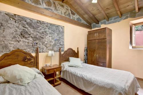 a bedroom with two beds and a stone wall at Casa Rural La Presa in Vallehermoso