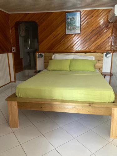 a bed with a wooden headboard and green sheets at LE VILLAGE DE CANADA in Faup