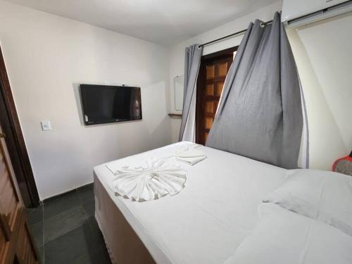a bedroom with a white bed and a television at Pé na Areia in Porto Seguro