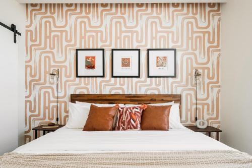 a bedroom with a bed and a wall with framed pictures at Gallery Retreat - Skyline Views - Zuni Lofts in Denver