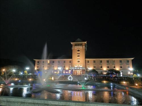 a building with a fountain in front of it at night at Jade Garden Hote in Gukeng