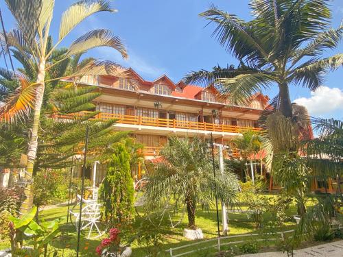 un bâtiment avec des palmiers en face de celui-ci dans l'établissement Esperanza Hotel - Oxapampa, à Oxapampa