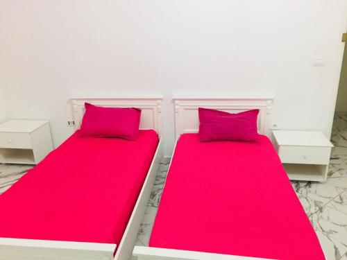 two beds in a room with red sheets at Nouveau Appartement Avec Un Parking Gratuit in La Marsa