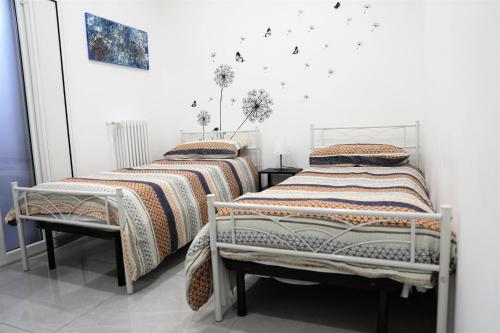 - 2 lits dans une chambre blanche avec des papillons sur le mur dans l'établissement Apulia Modern apartment - Bari Airport, à Bitonto