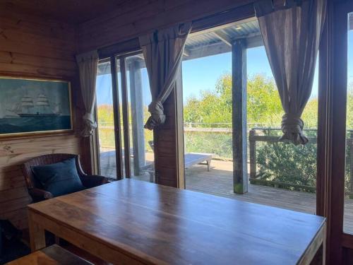 a wooden table in a room with a large window at Pt Hesse Luxury Coastal Homestead in Port Campbell