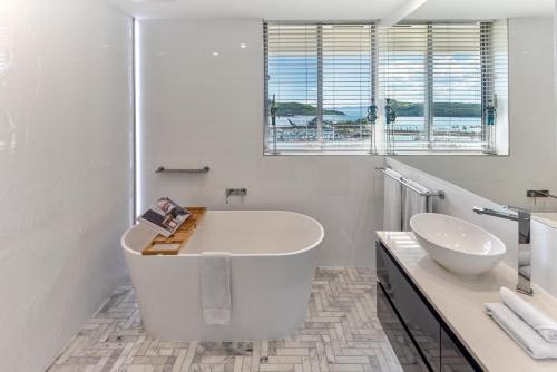 ein weißes Badezimmer mit einer Badewanne und einem Waschbecken in der Unterkunft Allure on Hamilton Island by HIHA in Hamilton Island