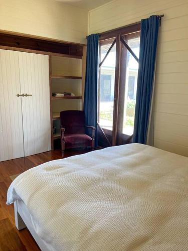 a bedroom with a bed and a chair and a window at Pt Hesse Luxury Coastal Homestead in Port Campbell