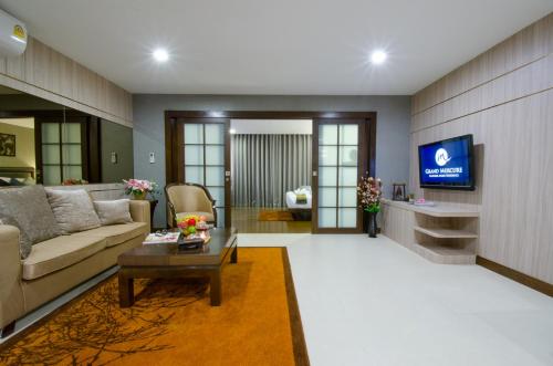 a living room with a couch and a tv at Grand Asoke Suites Boutique Residence in Bangkok