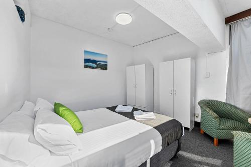 a bedroom with a bed and a green chair at Coach House Launceston in Launceston