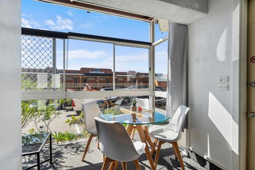 einen Balkon mit einem Tisch und Stühlen sowie einem großen Fenster in der Unterkunft Coach House Launceston in Launceston