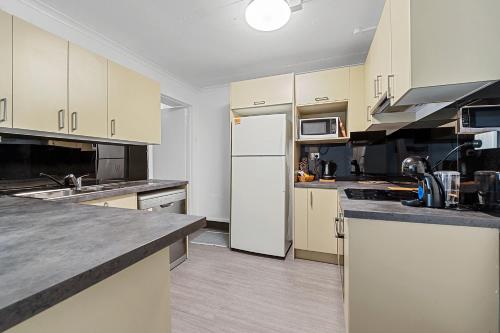 a kitchen with white cabinets and a white refrigerator at Coach House Launceston in Launceston