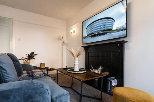 a living room with a couch and a tv on a wall at Finnieston 1-Bed - Walk to Hydro & Bars - Sleeps 2 in Glasgow
