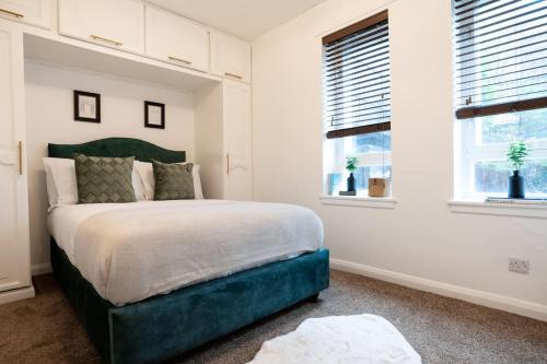 a bedroom with a large bed and two windows at The Hydro Escape - 5* Event Venue *Free Parking* in Glasgow