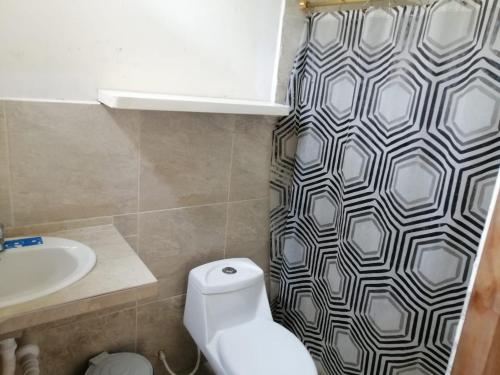 a bathroom with a toilet and a sink and a shower curtain at Casa Bony in Montañita