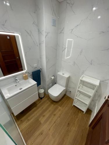 a white bathroom with a toilet and a sink at Monte Gordo South Pearl Apartment in Monte Gordo