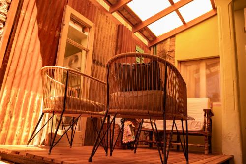 two chairs sitting on a porch with a window at VagaMundo Hostel Carhue in Carhué