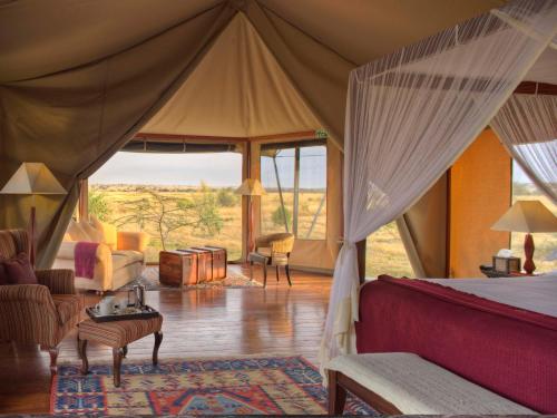 a bedroom with a bed and a living room at Olare Mara Kempinski in Talek
