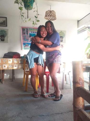 two women hugging each other in a room at Paraiso Hostel Moalboal in Moalboal