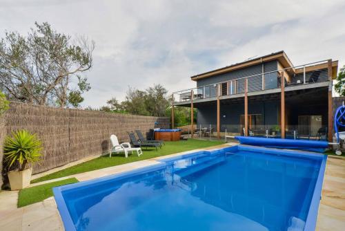 a swimming pool in front of a house at Moonah on Forbes in Rye