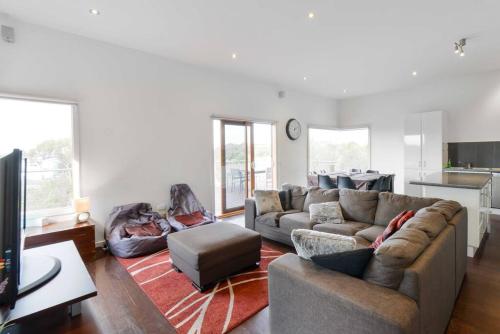 a living room with two couches and a kitchen at Moonah on Forbes in Rye