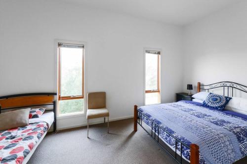 a bedroom with a bed and a chair and windows at Moonah on Forbes in Rye