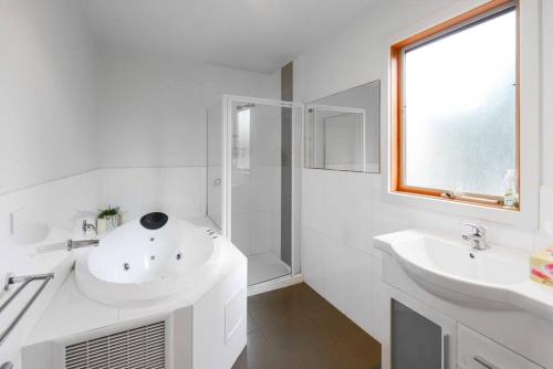 a white bathroom with two sinks and a shower at Moonah on Forbes in Rye