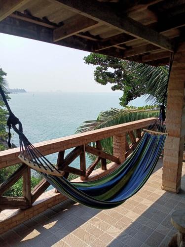 a hammock hanging from a fence next to the ocean at Cliff View Bungalows in Ko Chang