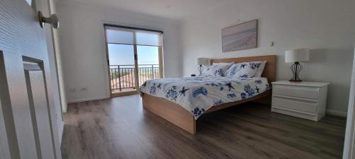 a white bedroom with a bed and a window at Shellharbour. Ocean, lake and mountain view in Shellharbour