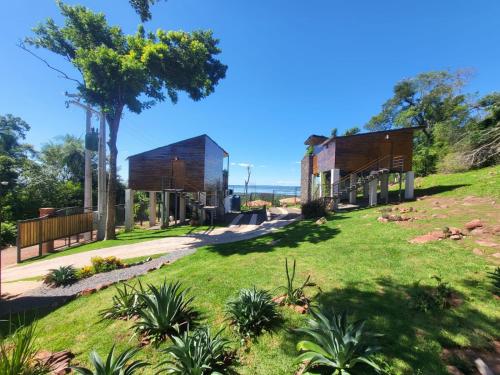 dwa domy na wzgórzu z trawą i drzewami w obiekcie Vista Lago Suites PY w mieście Itauguá