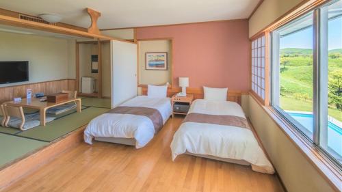 a hotel room with two beds and a television at Senomoto Kogen Hotel in Minamioguni