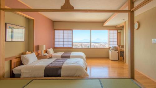 a bedroom with two beds and a large window at Senomoto Kogen Hotel in Minamioguni