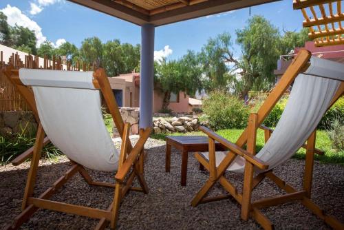two chairs sitting under an umbrella on a patio at Las Marías Hotel Boutique in Tilcara