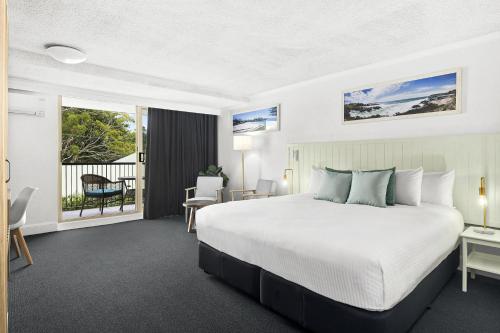 a bedroom with a large bed and a balcony at Kiama Shores in Kiama