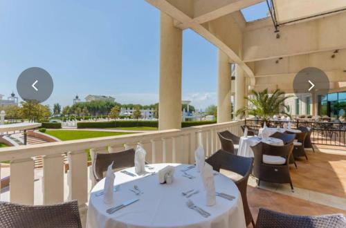 a restaurant with white tables and chairs on a balcony at "Красавиците тъмнокоси" Sunset Resort Pomorie in Pomorie
