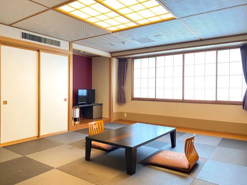 um quarto com uma mesa e cadeiras e uma televisão em Hotel Shinanoji em Nagano