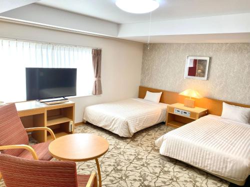 a hotel room with two beds and a tv at Hotel Shinanoji in Nagano